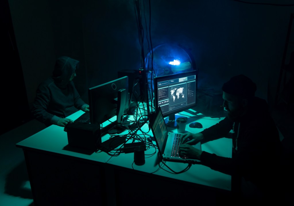 Photo of 2 hackers in office-like setting, evoking "As a service..." mentality for espionage